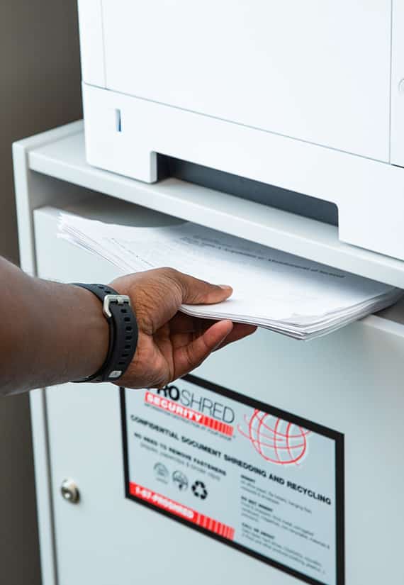 Man putting papers into a shredding console.