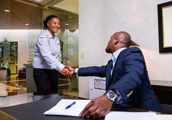 Business person and shredding employee shaking hands in an office.