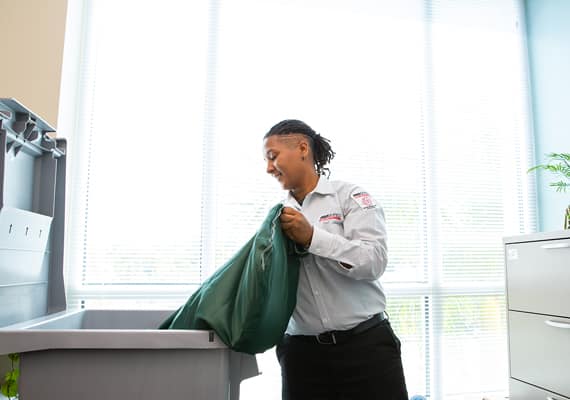 Employee unloading a bag of papers into a shredding bin.