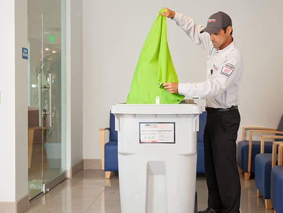 Service Tech using a Proshred bin.