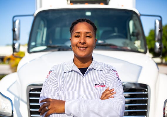 Shredding employee smiling with arms folded in front of a mobile shredding truck.