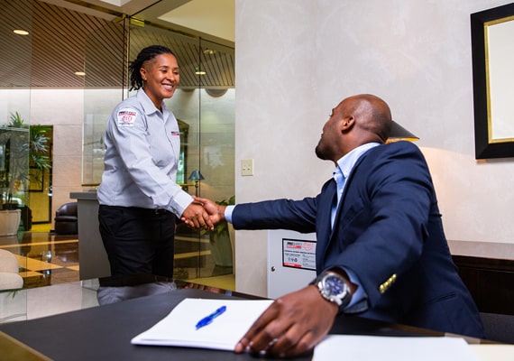Shredding company employee shaking hands with a businessman in an office.