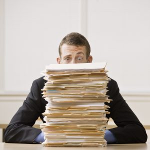 pile of documents with a man sitting behind them