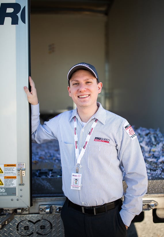 PROSHRED employee standing in front of destroyed paper documents.