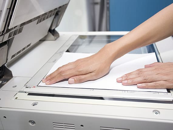 Professional woman putting paper documents into a shredding console.