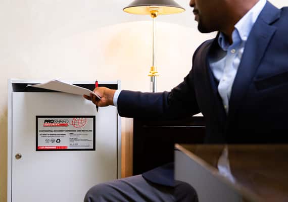 Businessman inserting papers into a document shredding console.