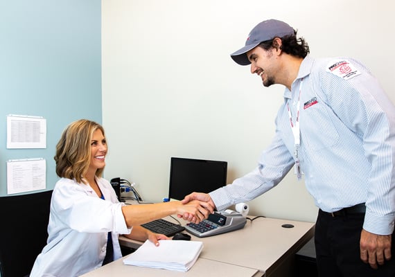 Medical office receptionist shaking hands with a document shredding professional.