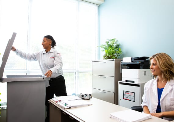 PROSHRED employee opening a document shredding bin in a medical office.