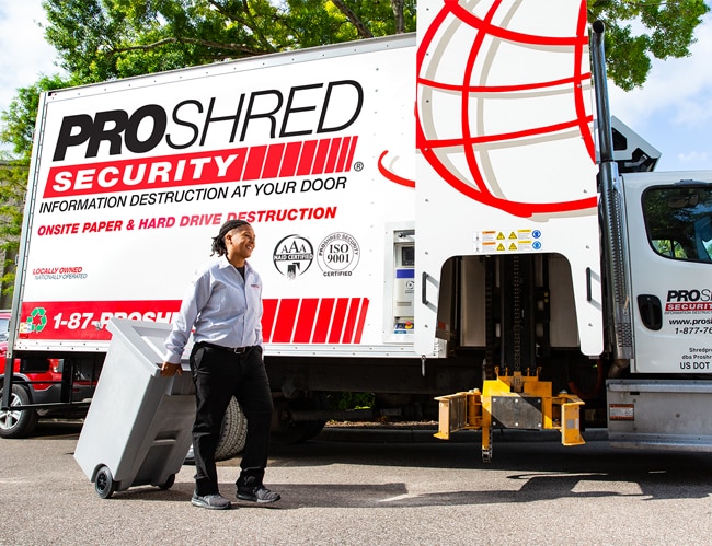 PROSHRED employee pulling a 96-gallon security bin to the mobile shredding truck.