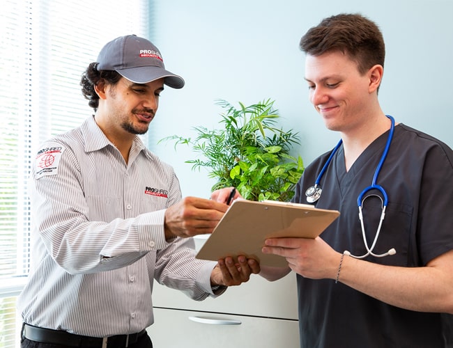 Proshred employee discussing a medical document shredding service agreement with a nurse.