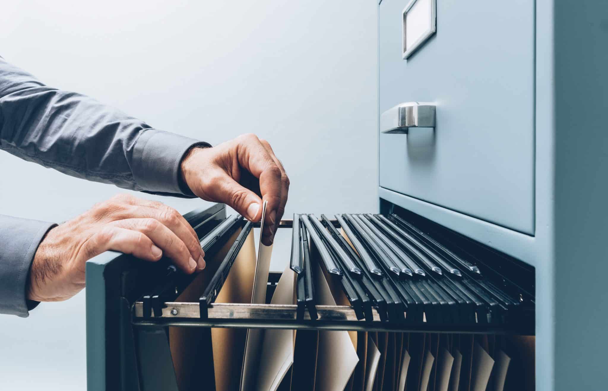 Business person searching for documents in a filing cabinet.