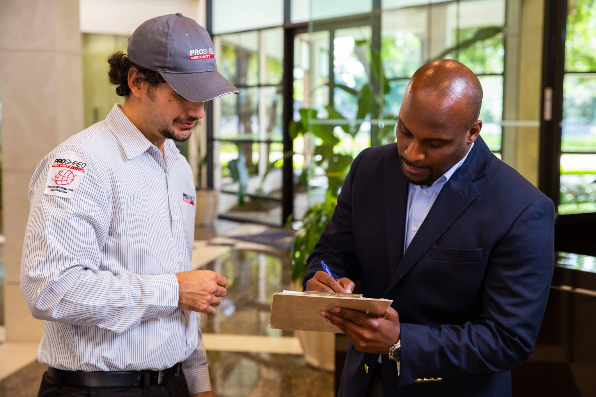 Businessman signing a document with a PROSCAN employee in an office.