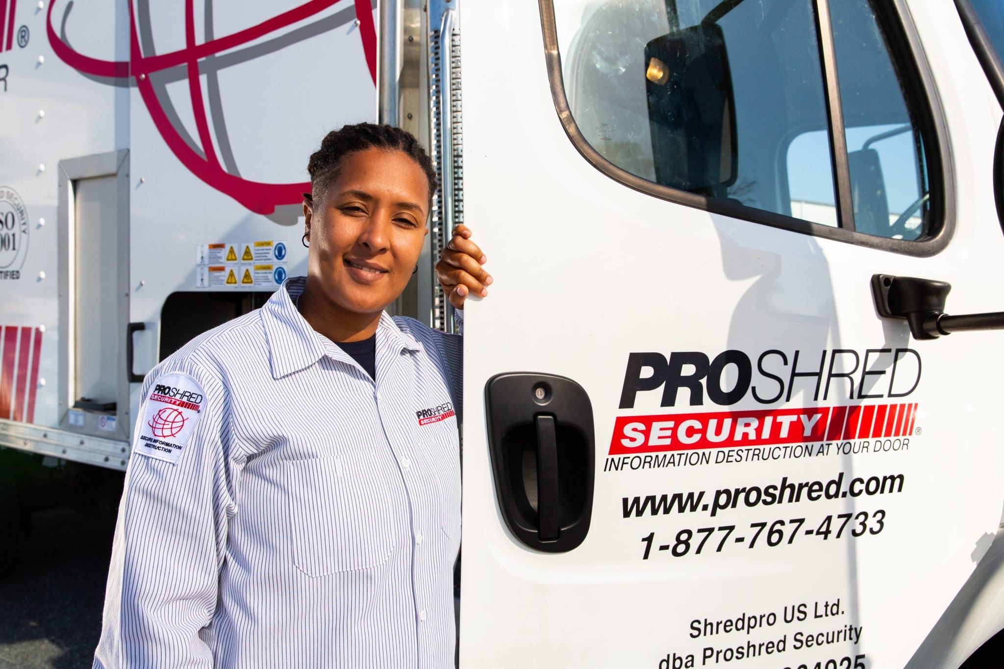 PROSHRED employee holding the door of a shredding truck.