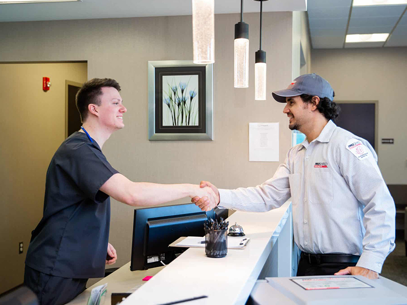 Shredding company employee and male nurse shaking hands.