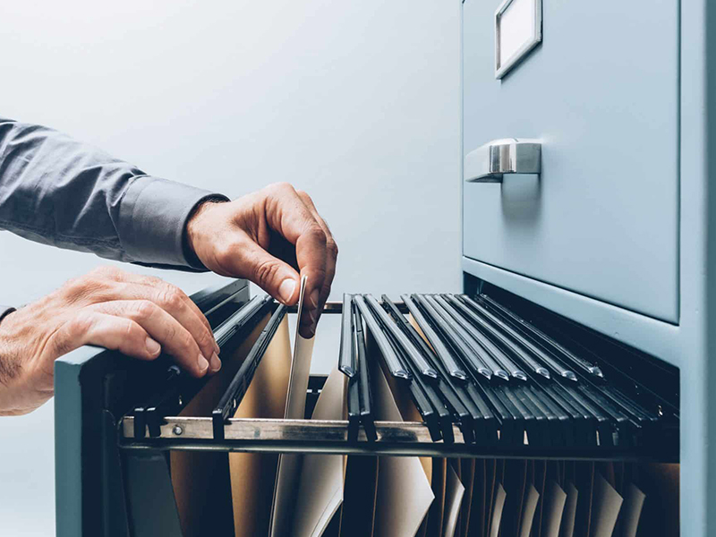 Business person searching for documents in a filing cabinet.