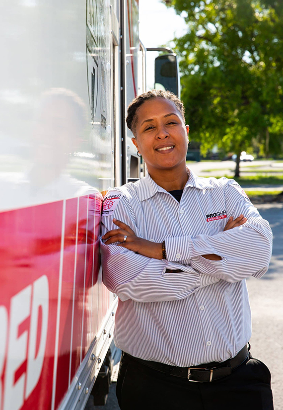 Employee standing beside a truck with folded arms.