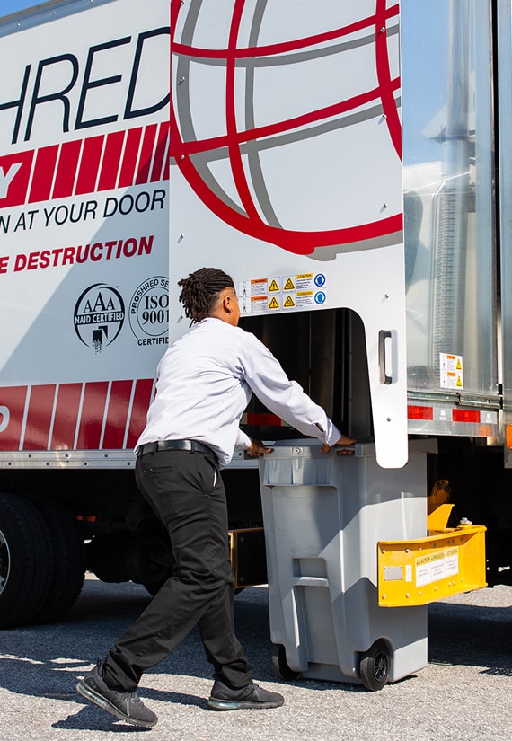 PROSHRED employee loading a shredding bin into a mobile truck.