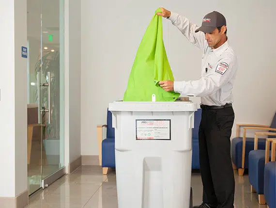 Proshred employee discarding confidential documents into a secure console bin to be shredded in our onsite shredding trucks