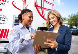 Shredding company employee and businesswoman discussing a contract outside by a mobile shred truck.