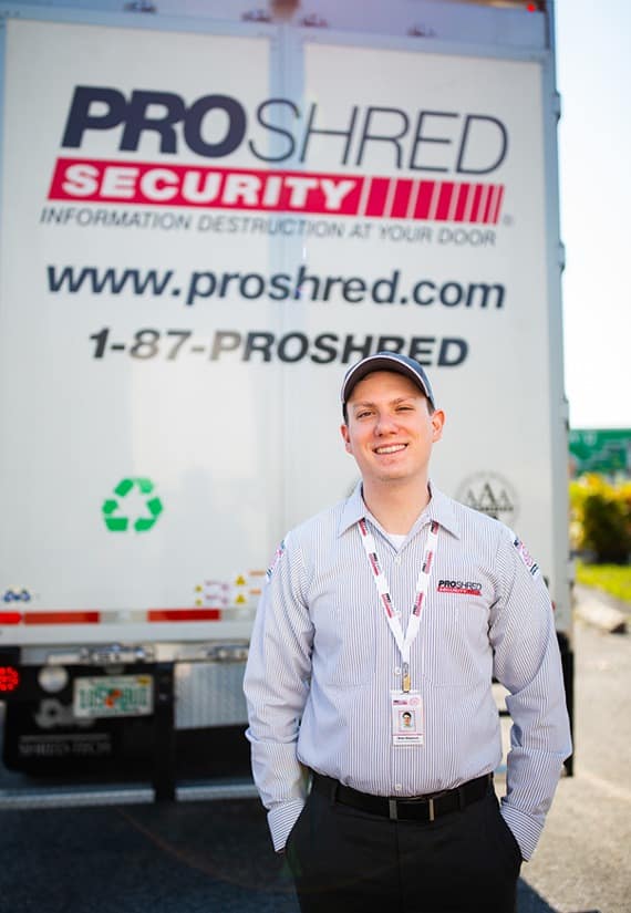 PROSHRED employee standing behind a mobile shredding truck.