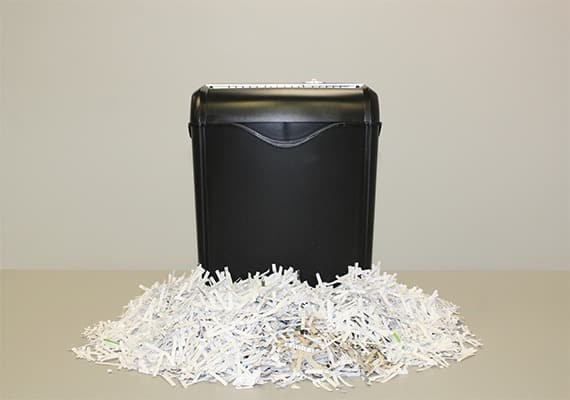 personal black shredder with a big pile of shredded documents