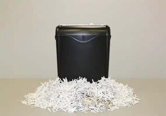 personal black shredder with a big pile of shredded documents