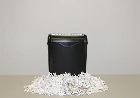 Personal home shredder with shredded papers around it.