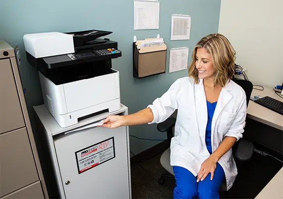 Health care professional discarding confidential documents into a proshred secure console bin