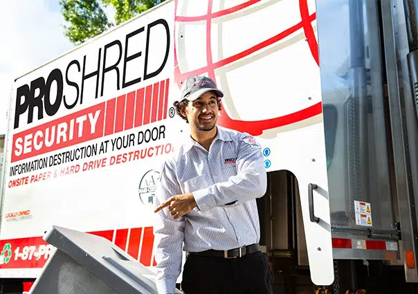 PROSHRED employee pulling a secure console bin that contains confidential information besides a PROSHRED shredding truck