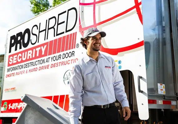 PROSHRED employee beside a PROSHRED shredding truck with a secure console bin