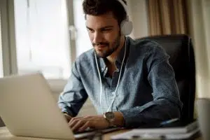 Young man working from a secure home office on his laptop with organized files on the desk.