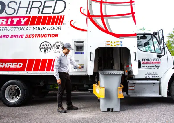 grey shredding bin in front of shredding truck