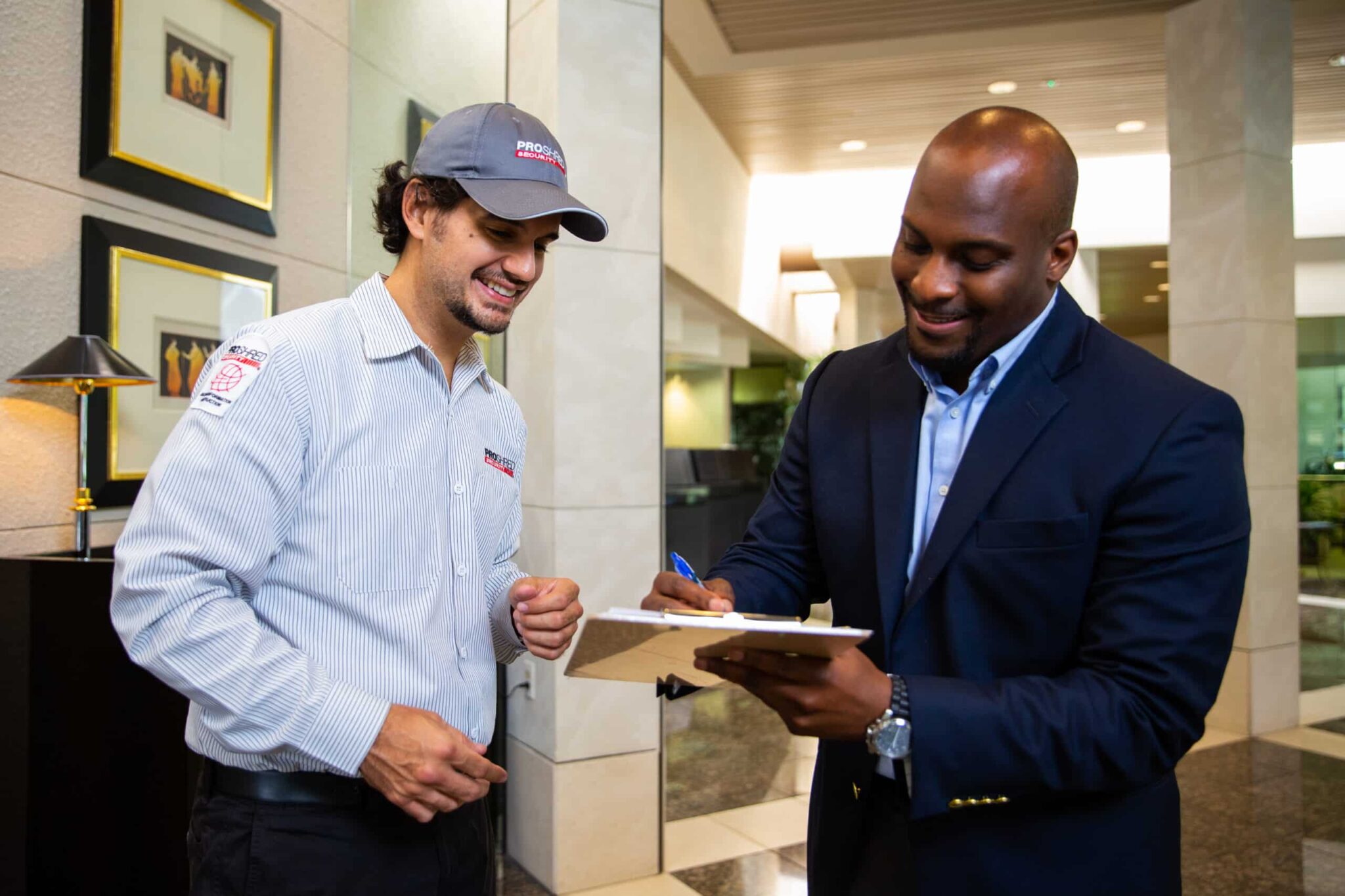 man in suit signing on a clipboard while man in shredding uniform looks on