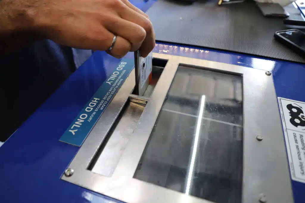 A Proshred employee inserts a hard drive into the shredder for destruction.